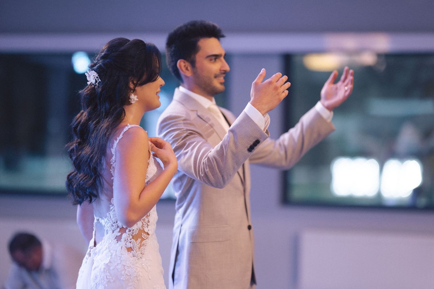 Elegant wedding guests dance together on a dimly lit ballroom floor.