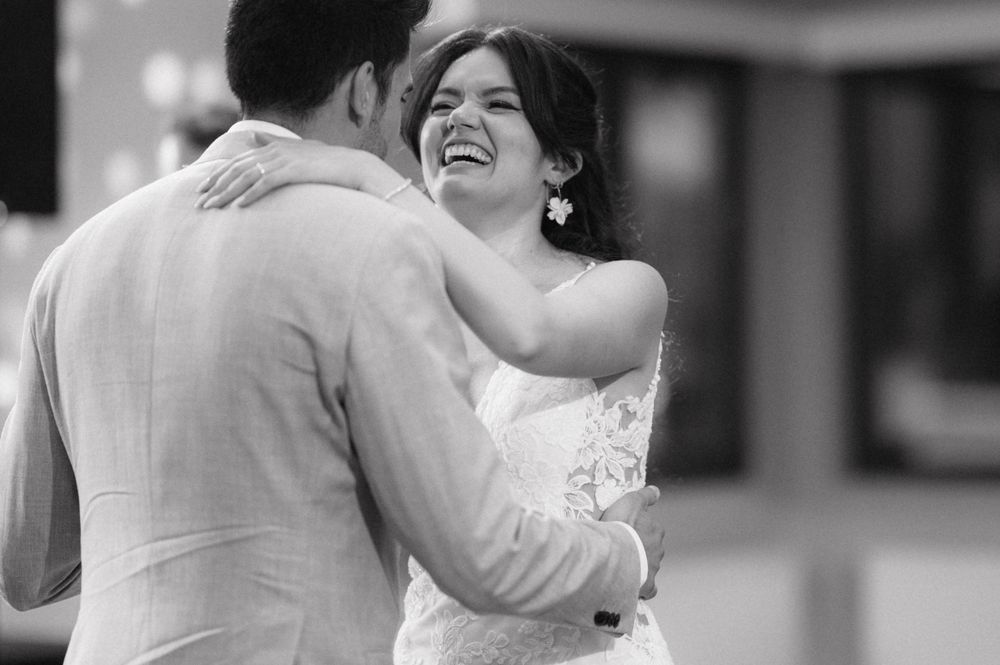 A tender moment during a wedding as newlyweds embrace in happiness, captured in black and white photography.