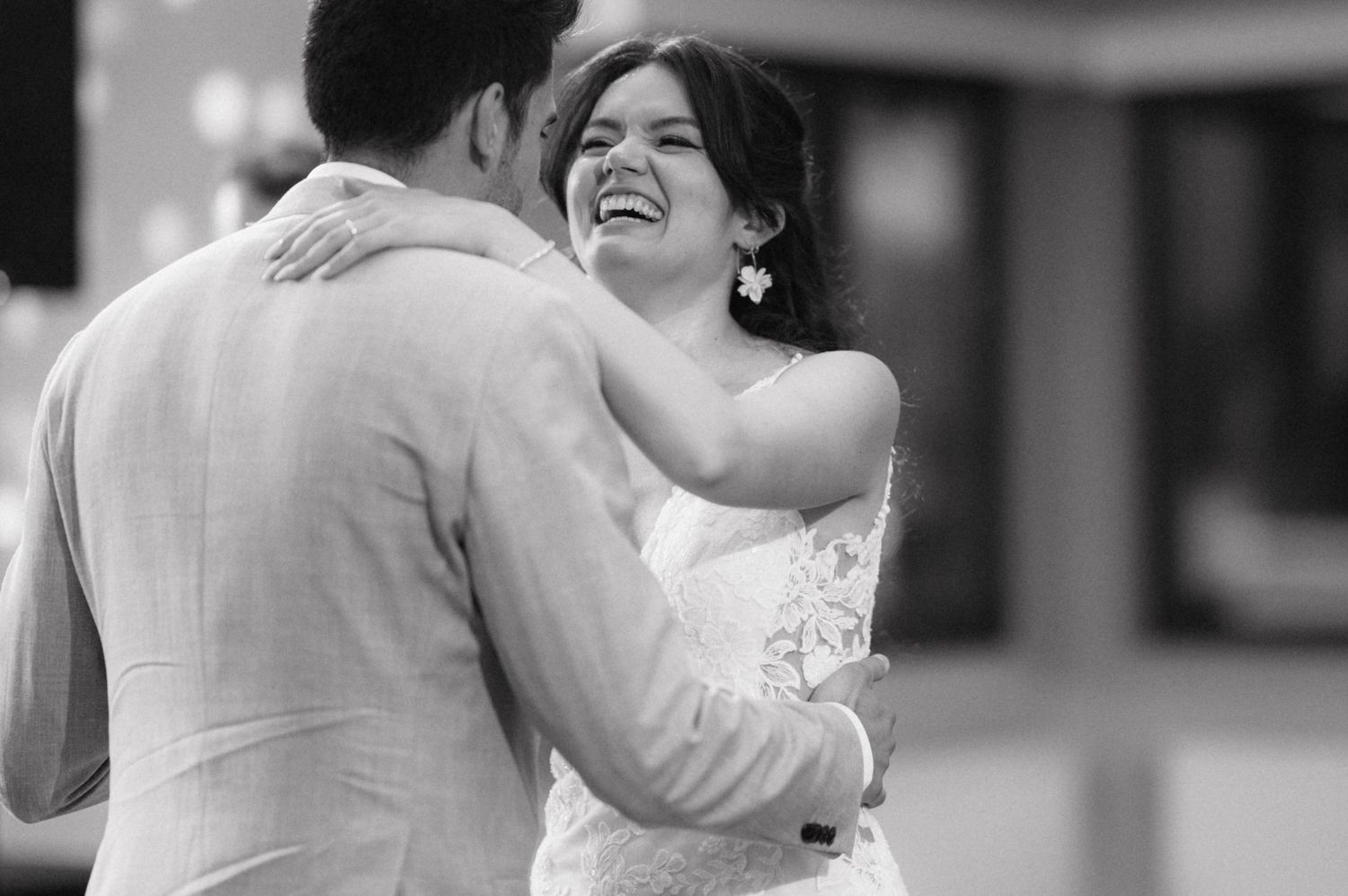 A tender moment during a wedding as newlyweds embrace in happiness, captured in black and white photography.