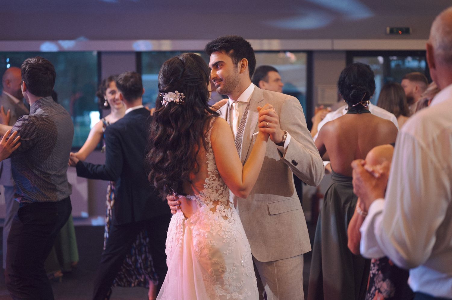 Wedding guests dancing and celebrating on a dimly lit dance floor during a reception party.