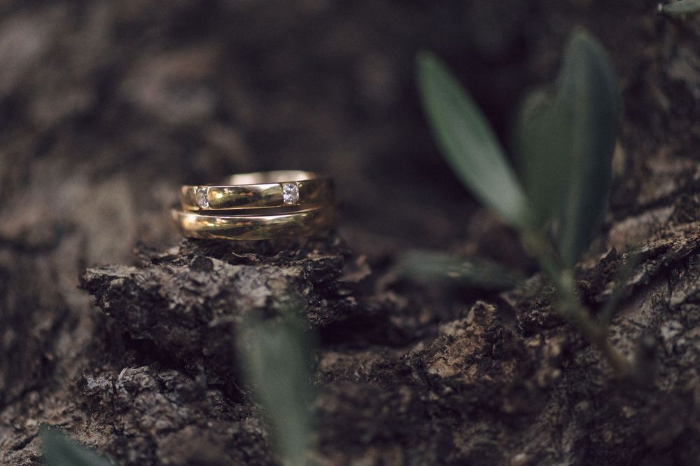 Wedding rings photographed in artistic macro detail against a dark textured background.