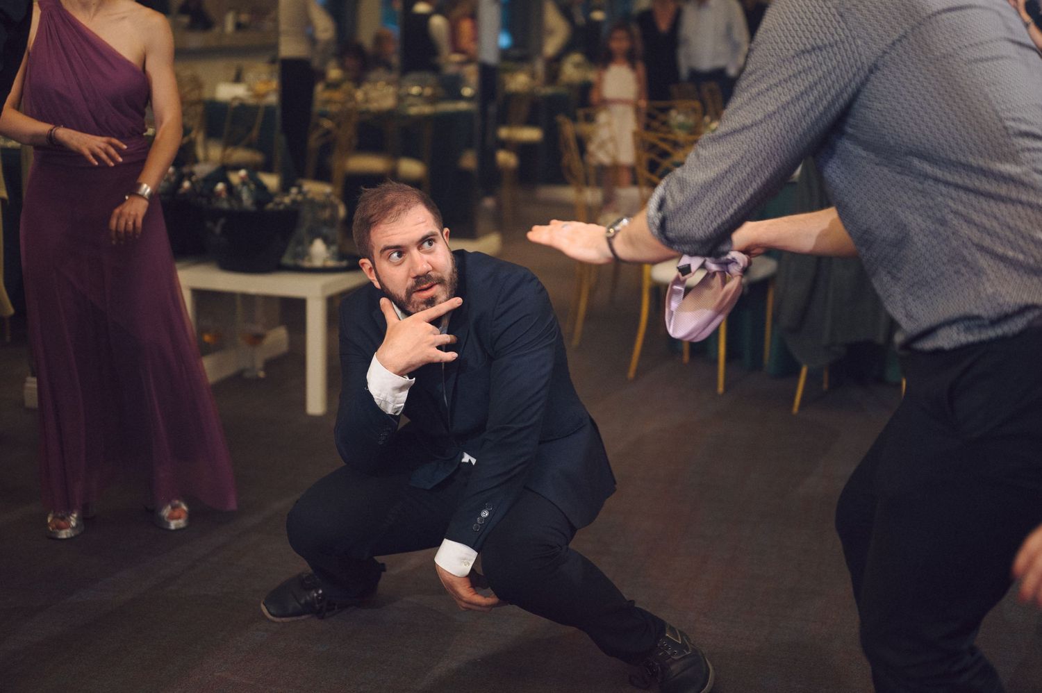 People dancing while bending low in synchronized dance moves at a wedding reception.
