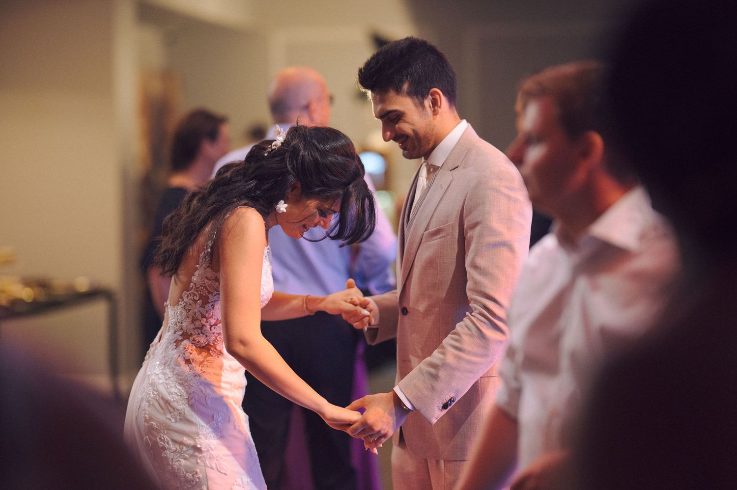 Couple dancing intimately during a wedding reception in soft lighting.