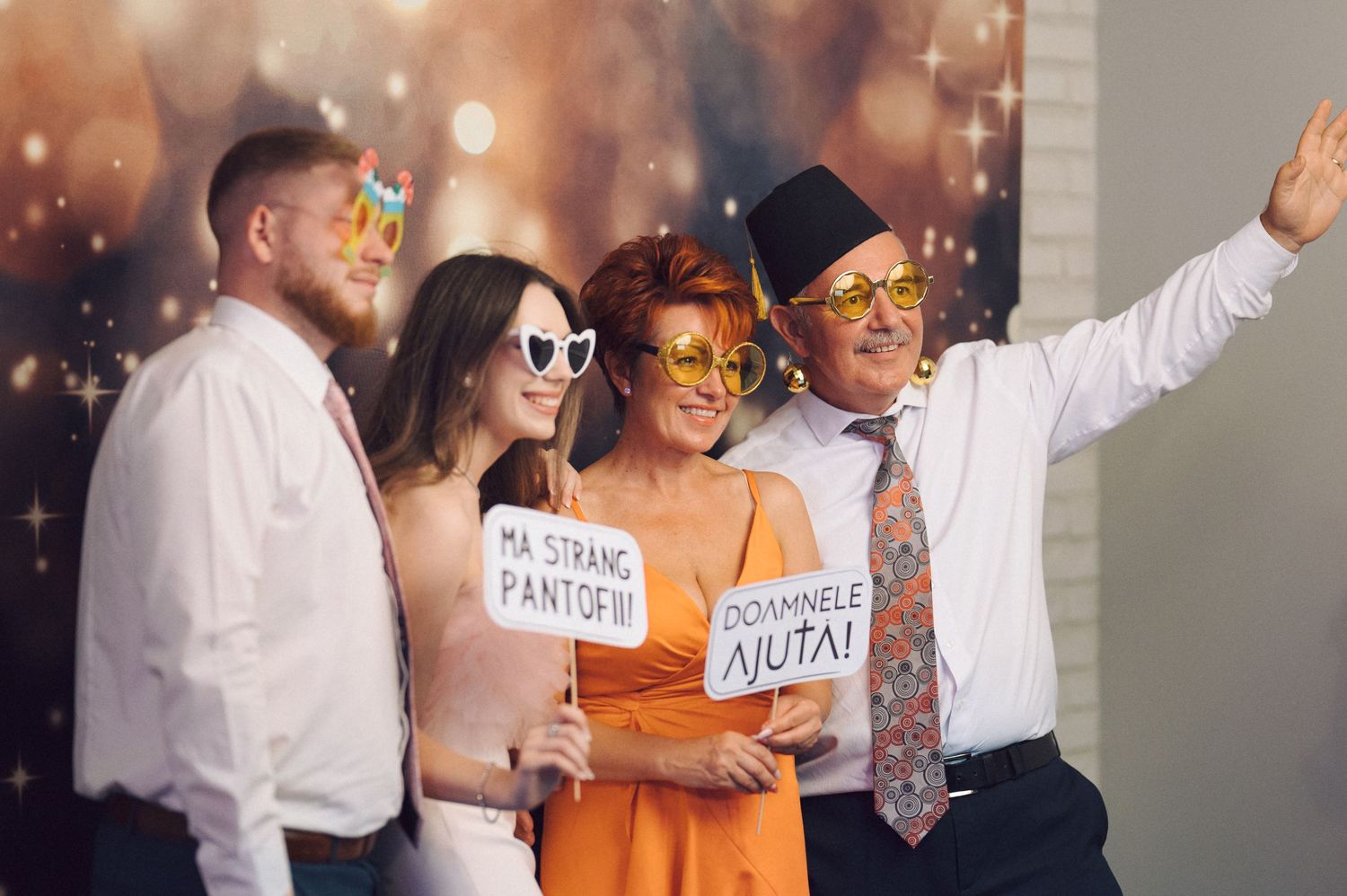 Wedding party guests dance together holding signs while enjoying a celebration with sparkly lighting effects.