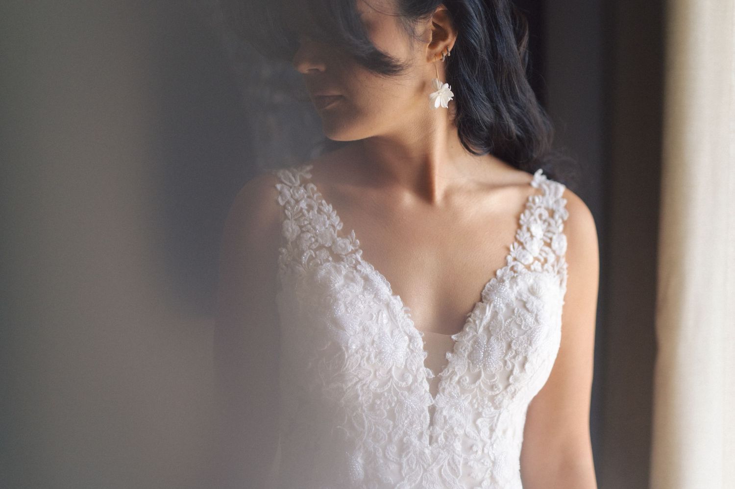 Close-up details of an elegant lace wedding dress with delicate floral embellishments and beading along the neckline.