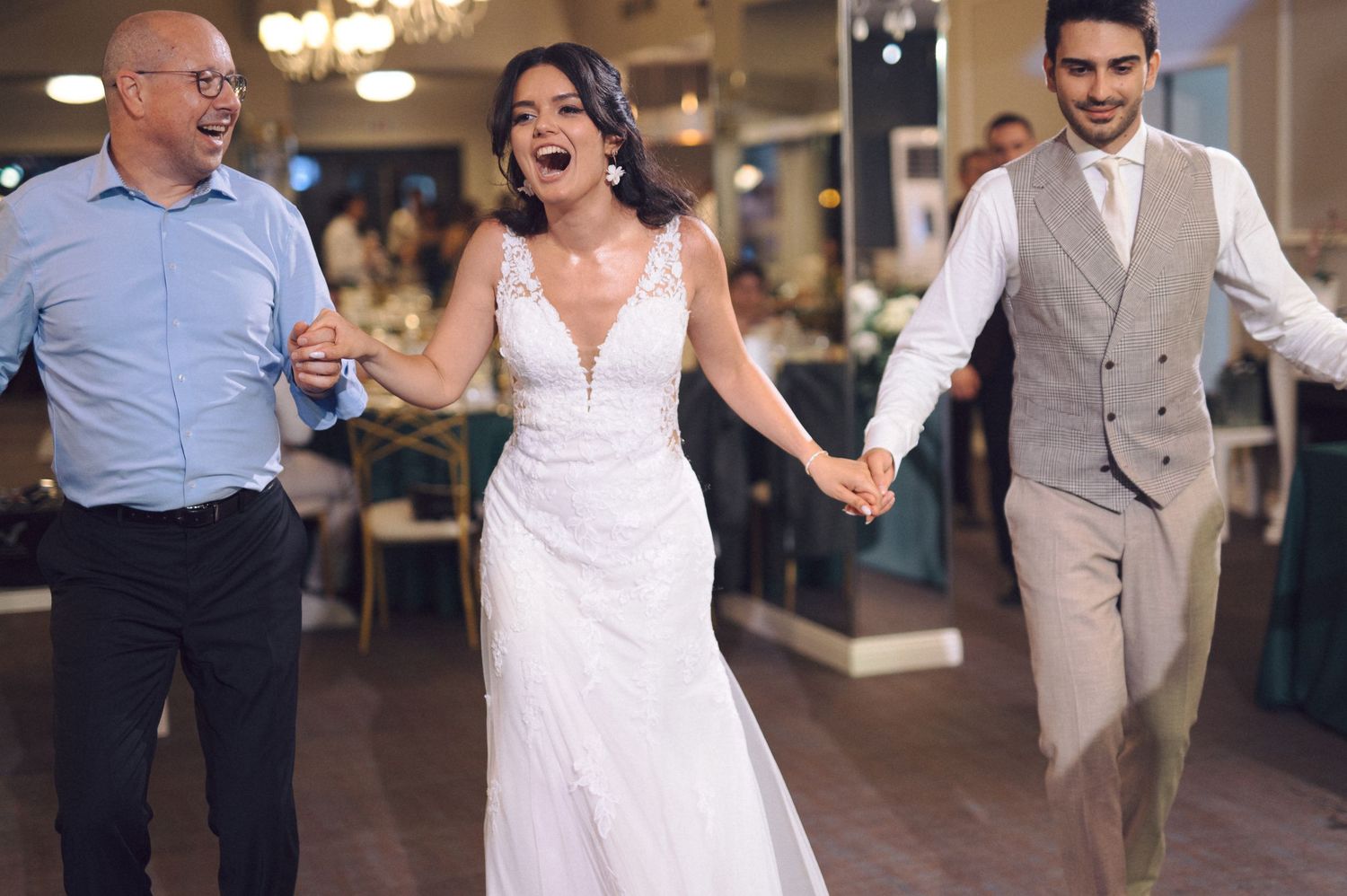 Wedding celebration scene with people dancing joyfully in an indoor venue.