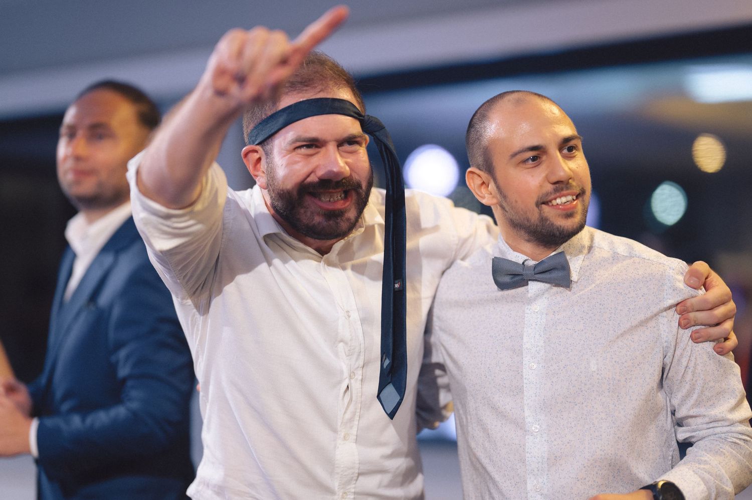 Party guests in formal attire gesture and celebrate animatedly at an evening event.