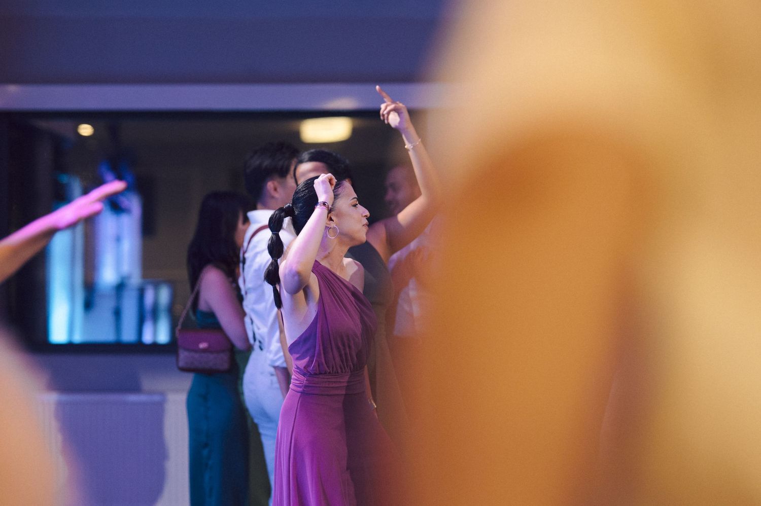 Couples dancing together at an elegant indoor event with atmospheric blue lighting.