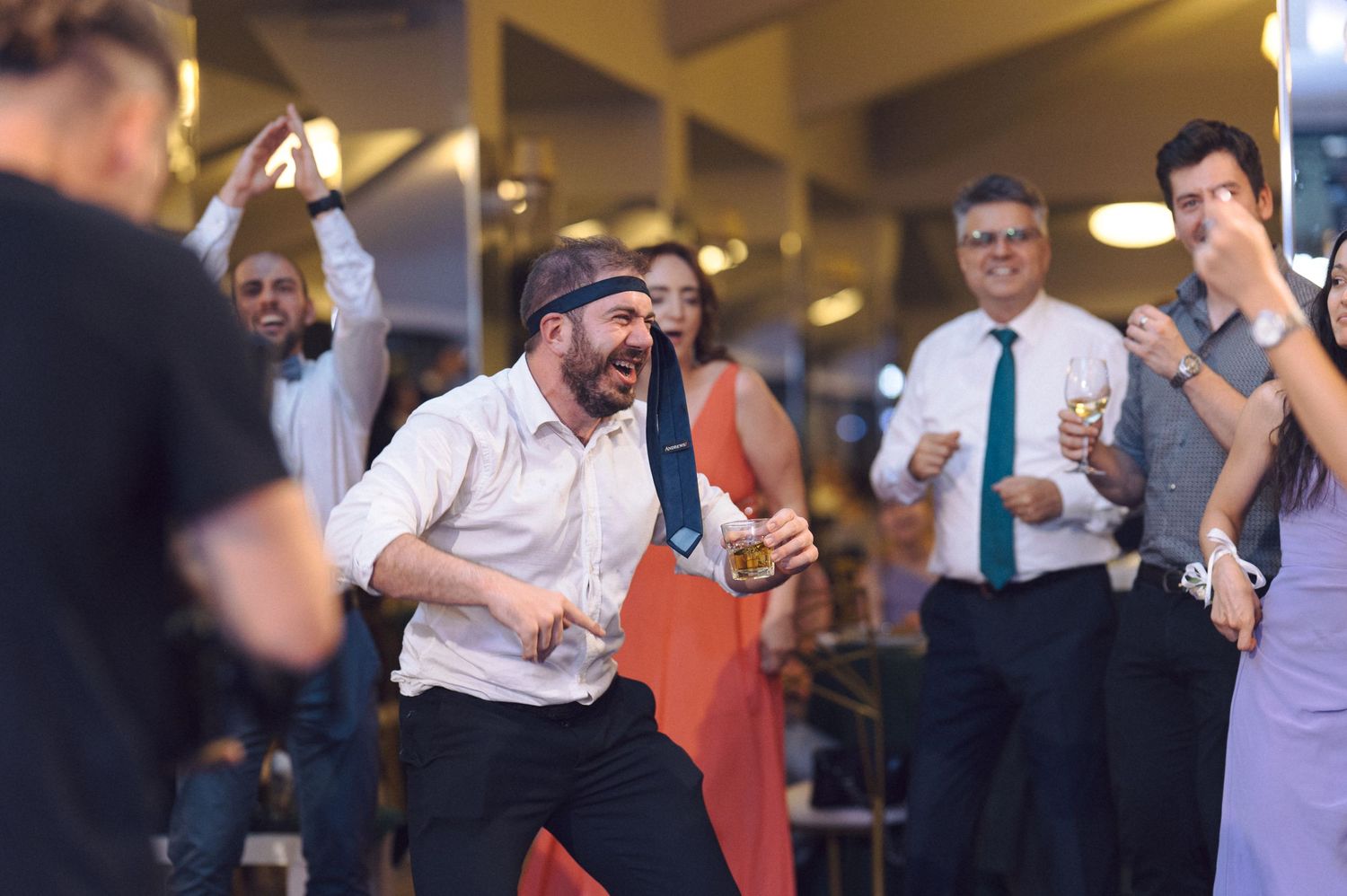 Celebration attendees dancing and mingling at a festive indoor event with ambient lighting.