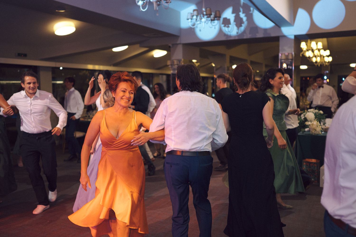 A festive dance party scene shows people dancing and swaying to music in formal attire.