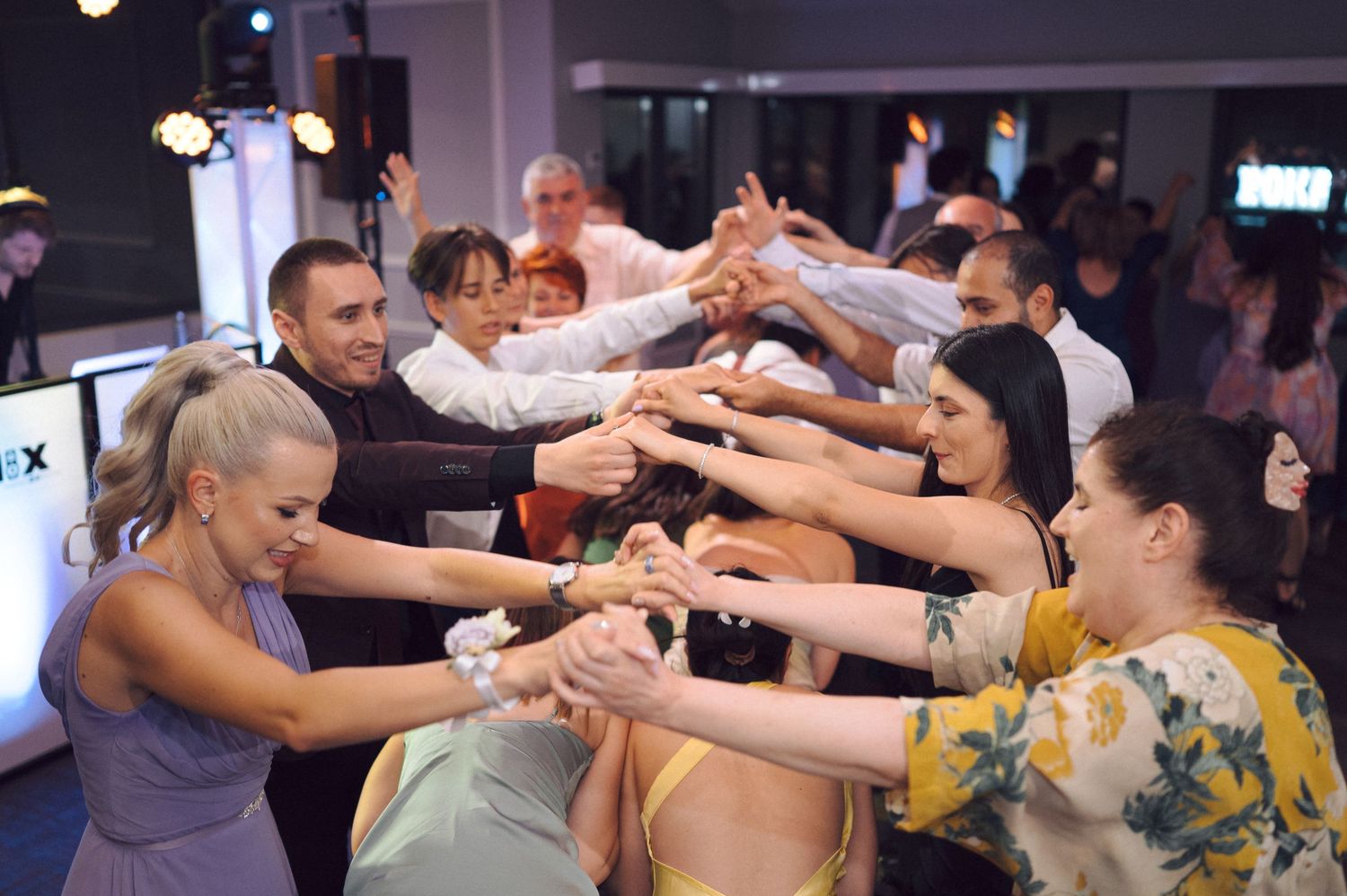 People dancing and celebrating during a lively party with hands raised in synchronized motion.