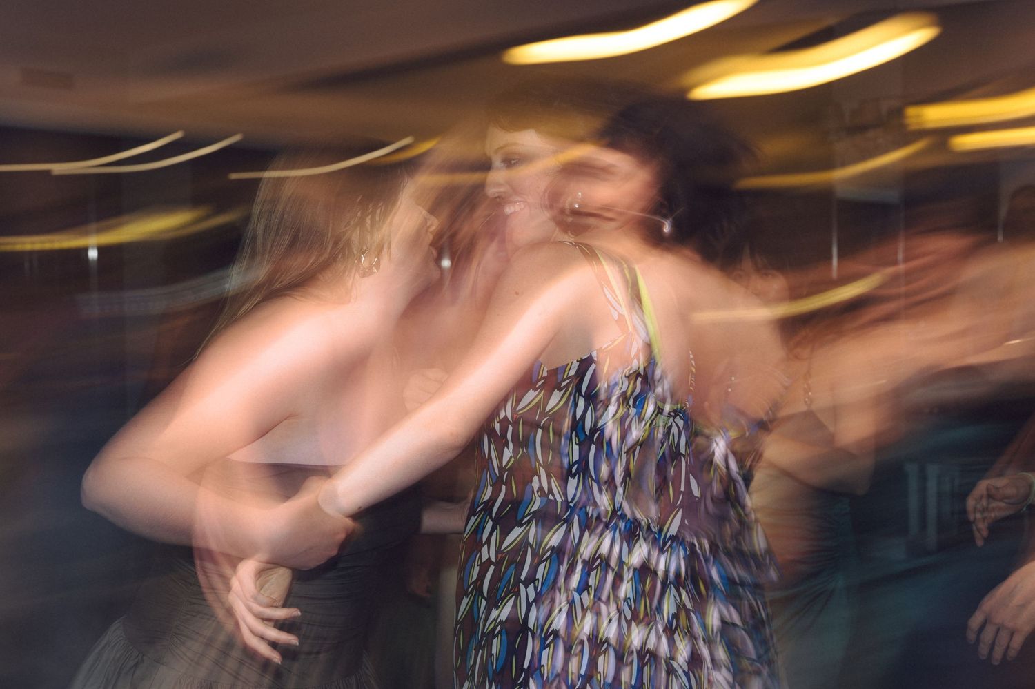Motion blur captures a dancer in a patterned dress creating an ethereal effect during movement at an indoor venue.