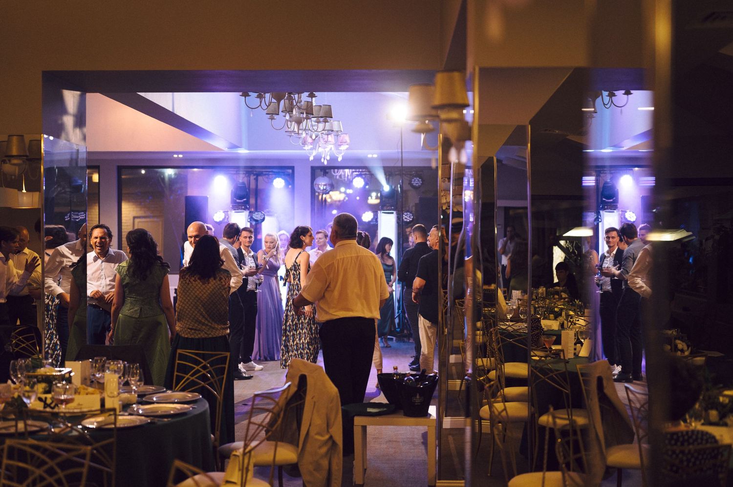 Dimly lit venue interior showing tables and chairs arranged for an evening event.