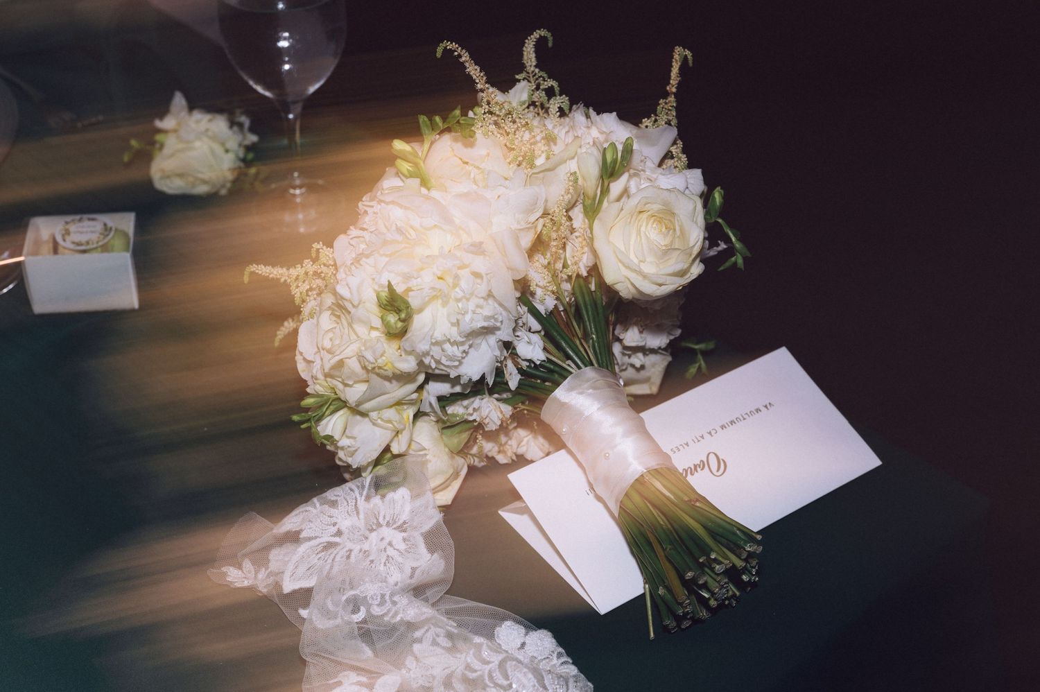 Elegant white rose centerpieces and place cards arranged on dark table settings.