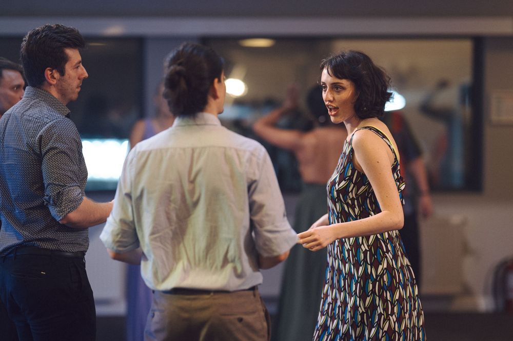 Dance partners performing social dance moves on a dimly lit dance floor during an evening event.