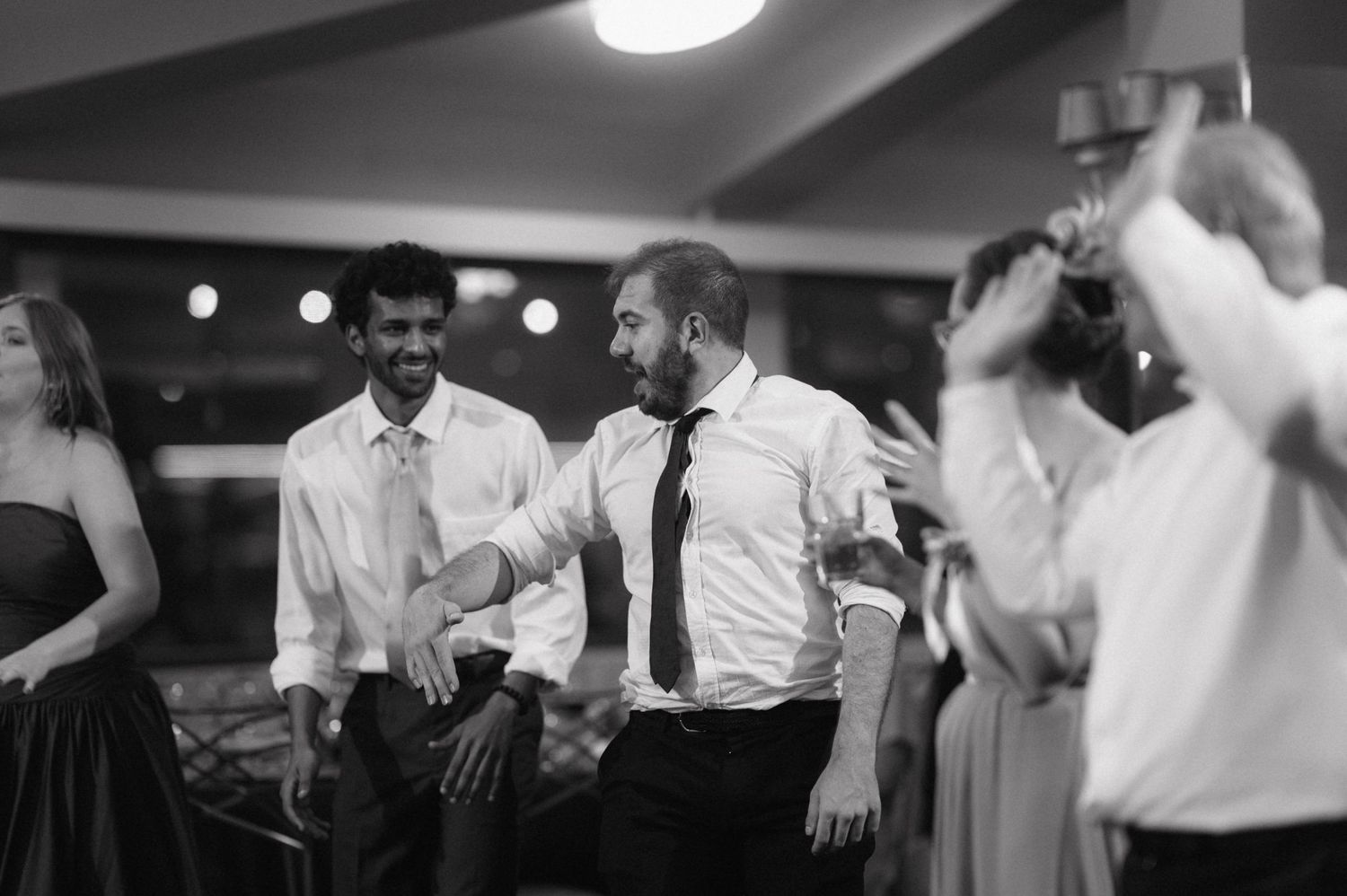 A black and white photo shows people dancing together at a lively reception party.