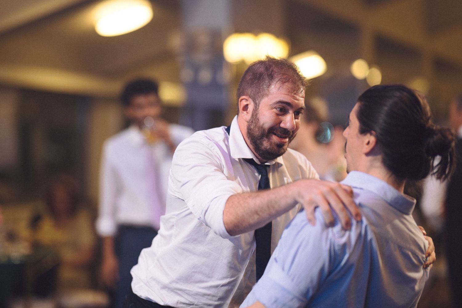 Wedding couple dances together joyfully on a dance floor during their reception celebration.