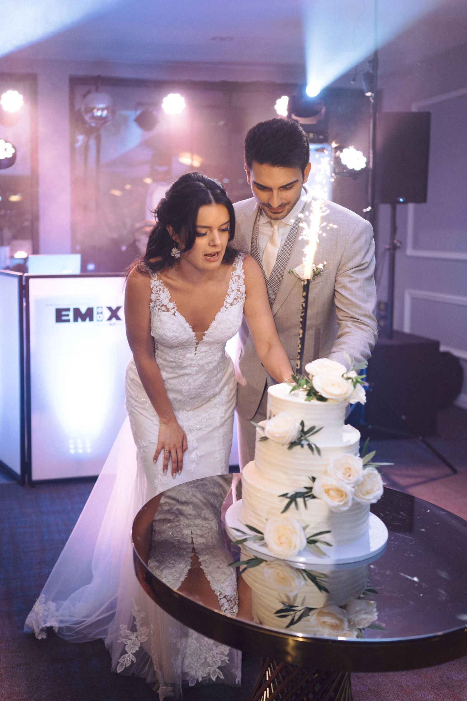 Wedding couple slices into their elegant white tiered cake with black accents during their reception celebration.