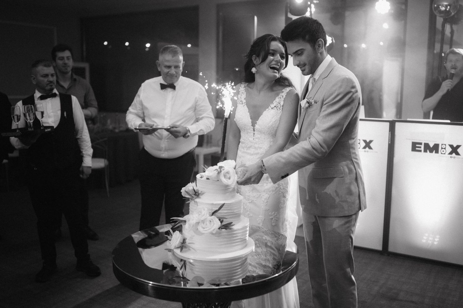 Bride and groom cut their white wedding cake together during the traditional reception moment.