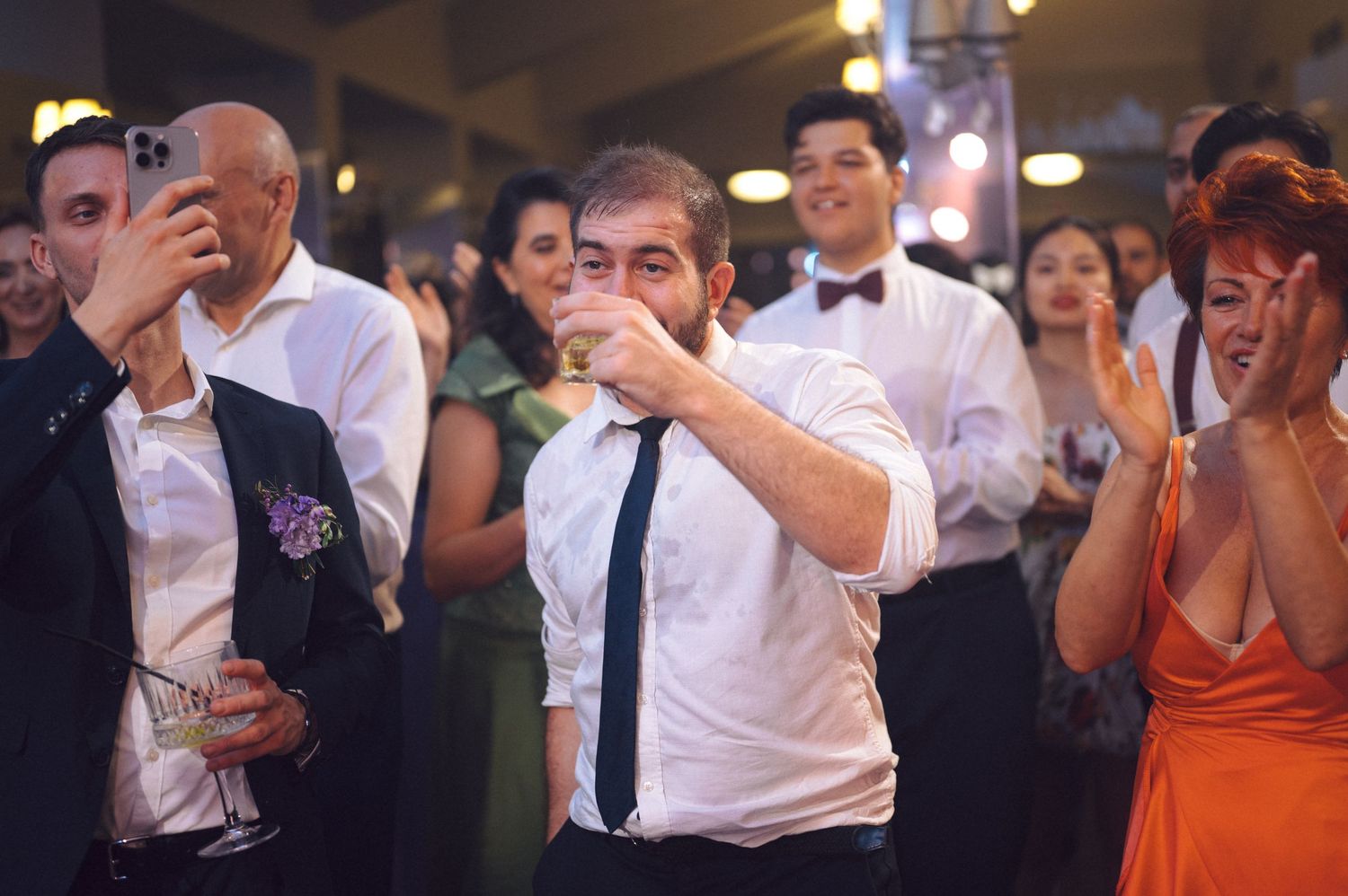 A series of people dancing and celebrating together at an upbeat wedding reception on a dance floor.