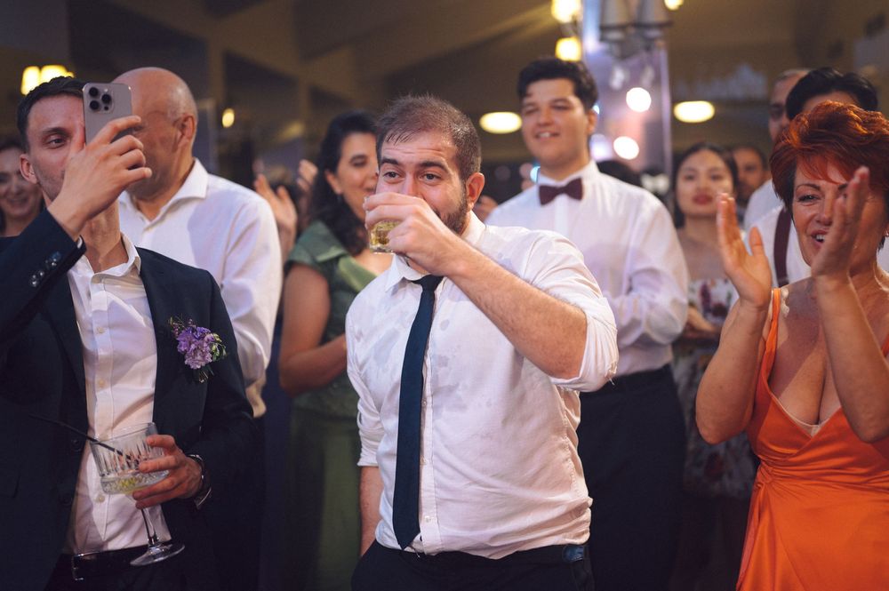 A series of people dancing and celebrating together at an upbeat wedding reception on a dance floor.