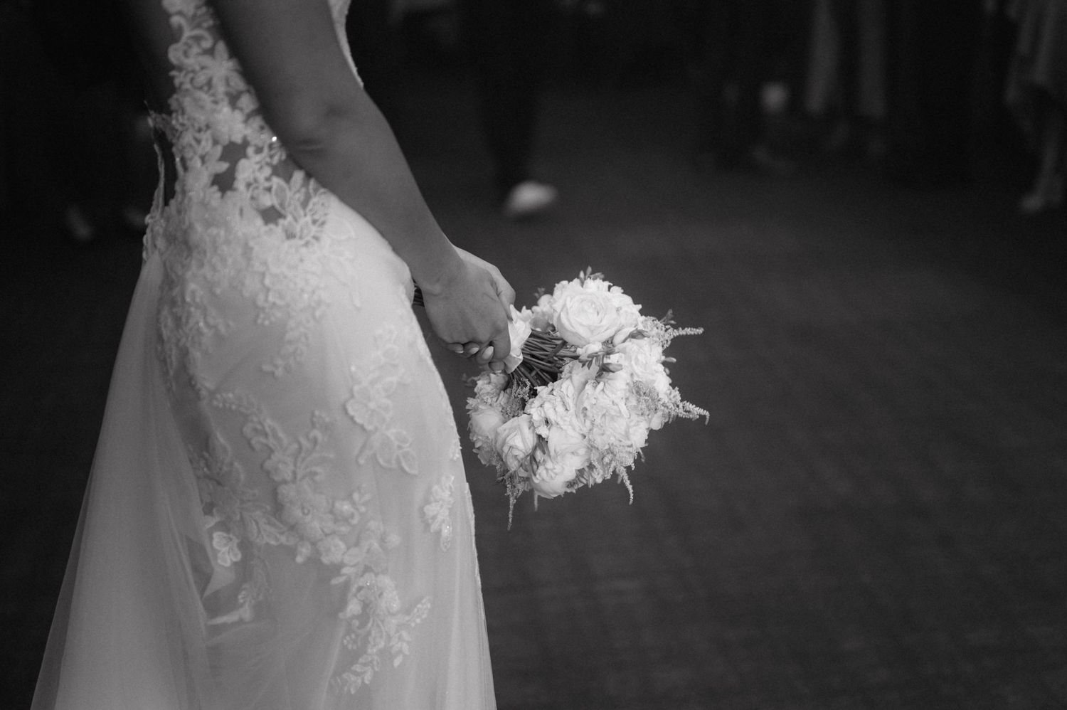 A black and white detail shot shows a bride holding a delicate white bouquet against her lace wedding dress.