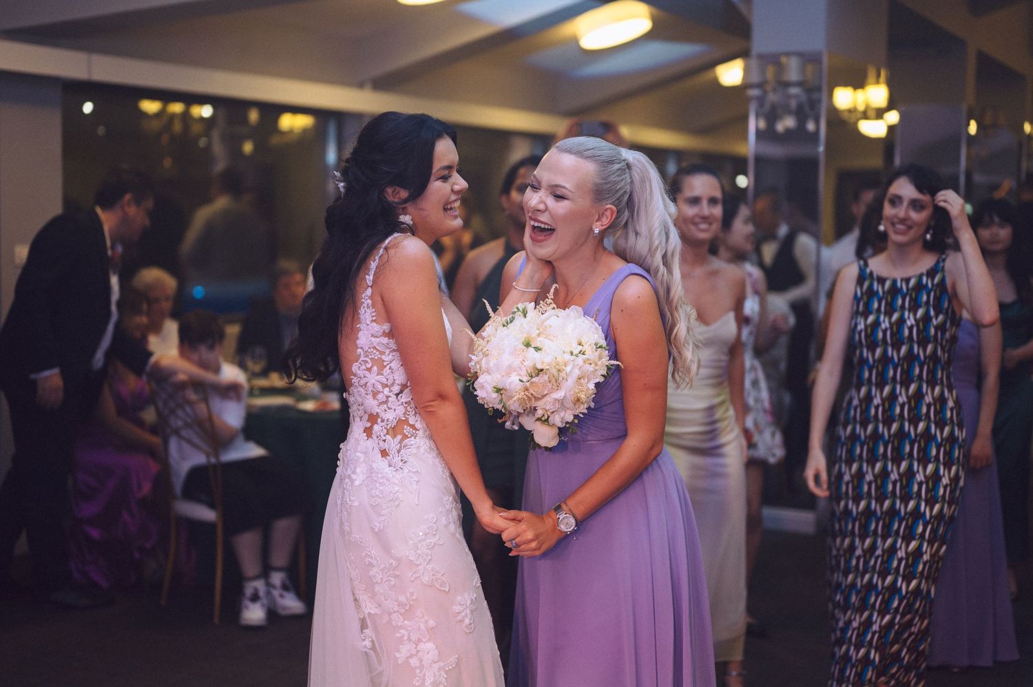 Wedding party members in purple dresses dancing and having fun at an evening reception.