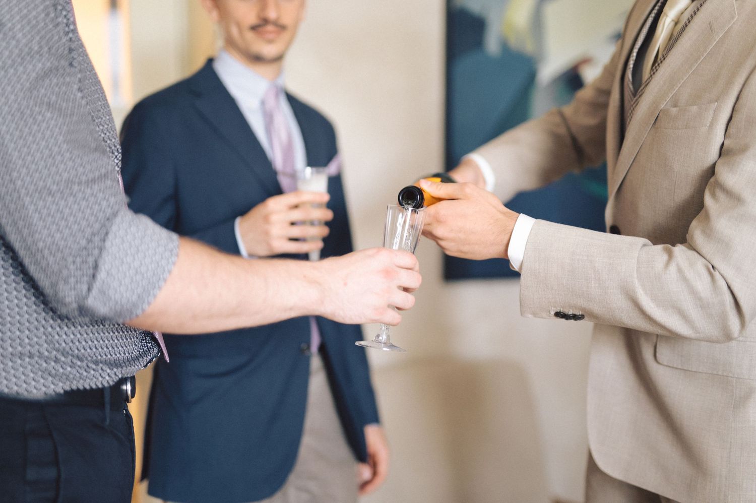 Business professionals in formal attire gather together holding beverages during a networking event.