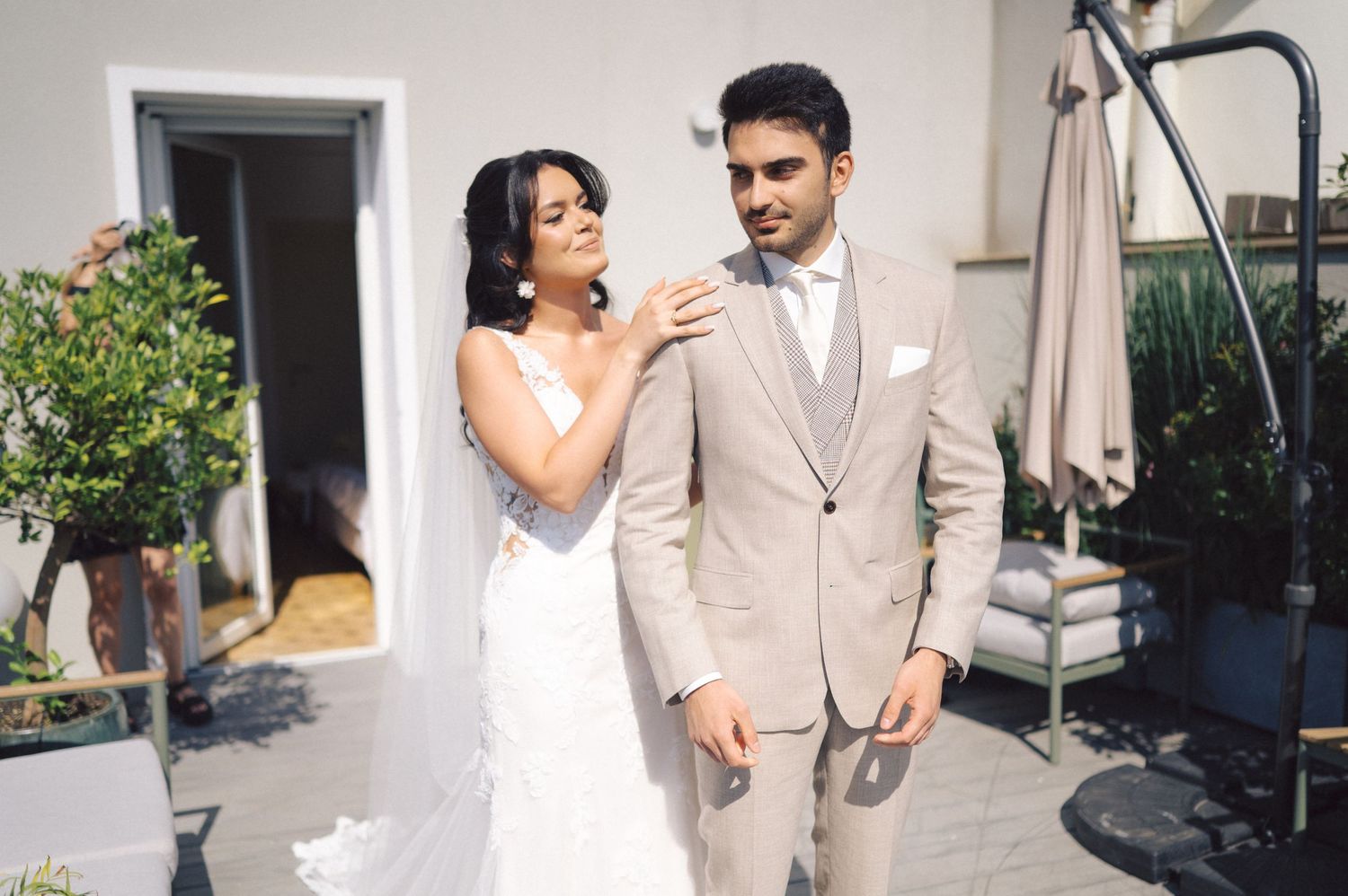 A couple shares a joyful moment together outdoors during their wedding ceremony, wearing beige and white attire.