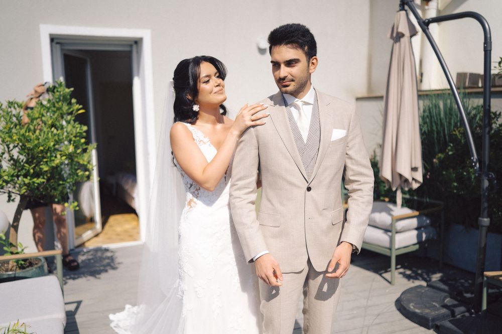 A couple shares a joyful moment together outdoors during their wedding ceremony, wearing beige and white attire.