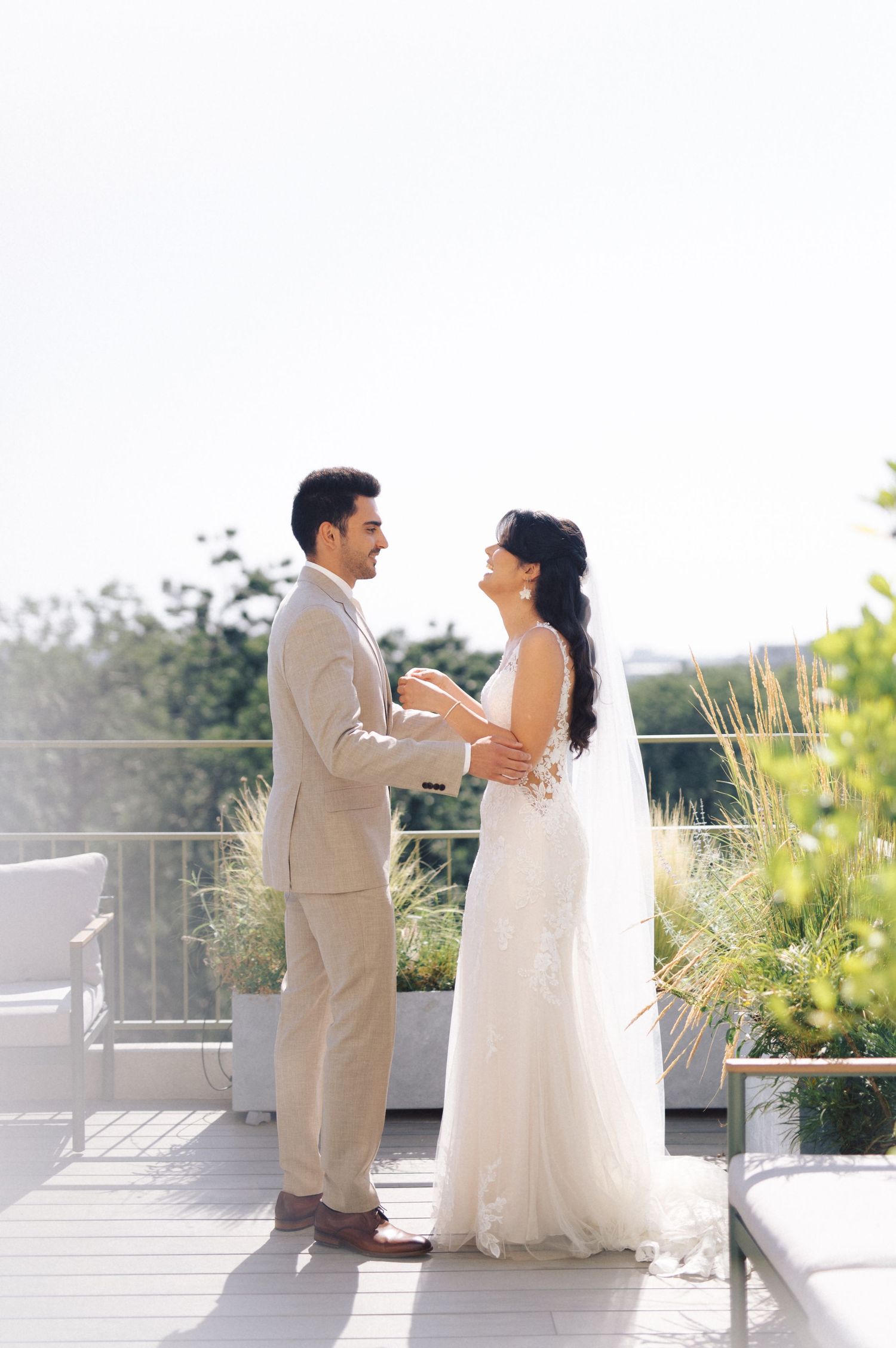 A couple shares a tender moment on an outdoor terrace during their wedding celebration.
