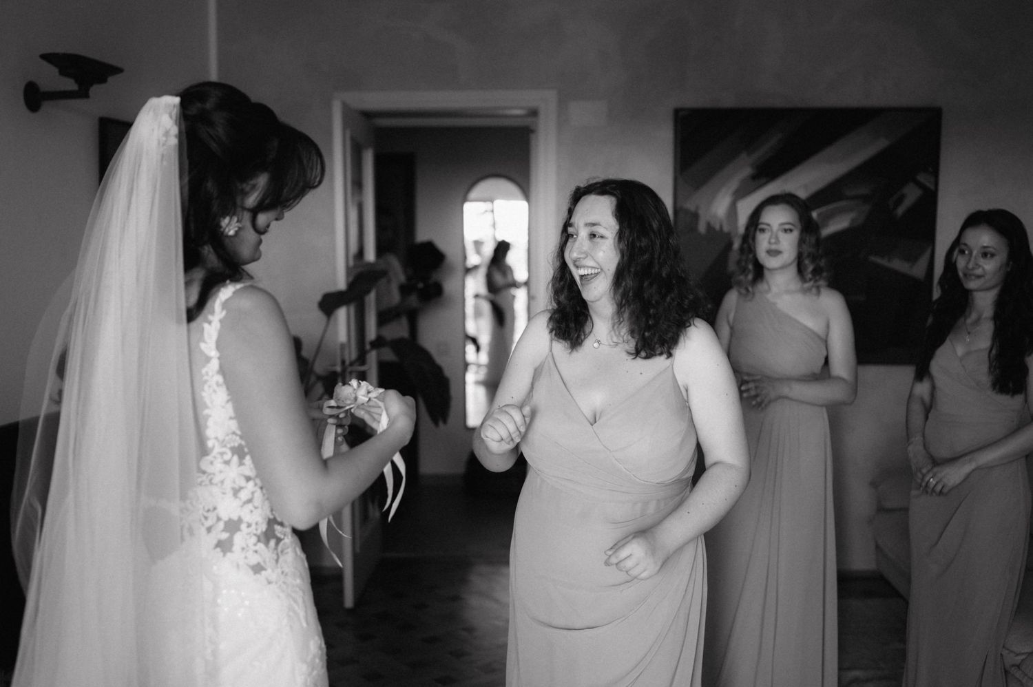 A black and white candid emotional moment among women gathering and celebrating at an indoor wedding celebration.