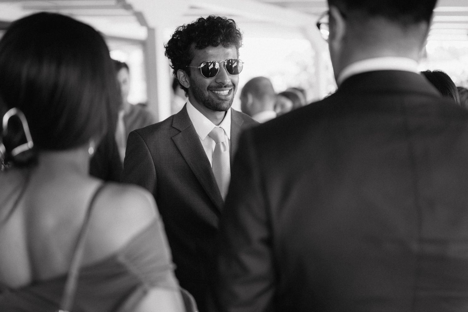 A black and white candid moment at a formal gathering showing people engaged in conversation.