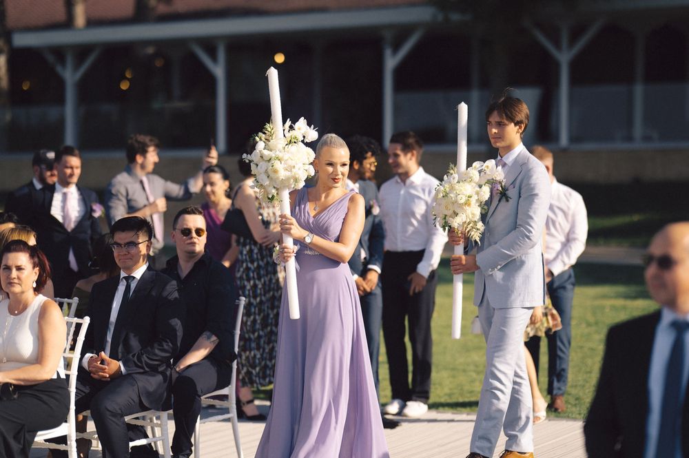 Outdoor wedding ceremony in progress with bridesmaids in lavender dresses and groomsmen in light grey suits.