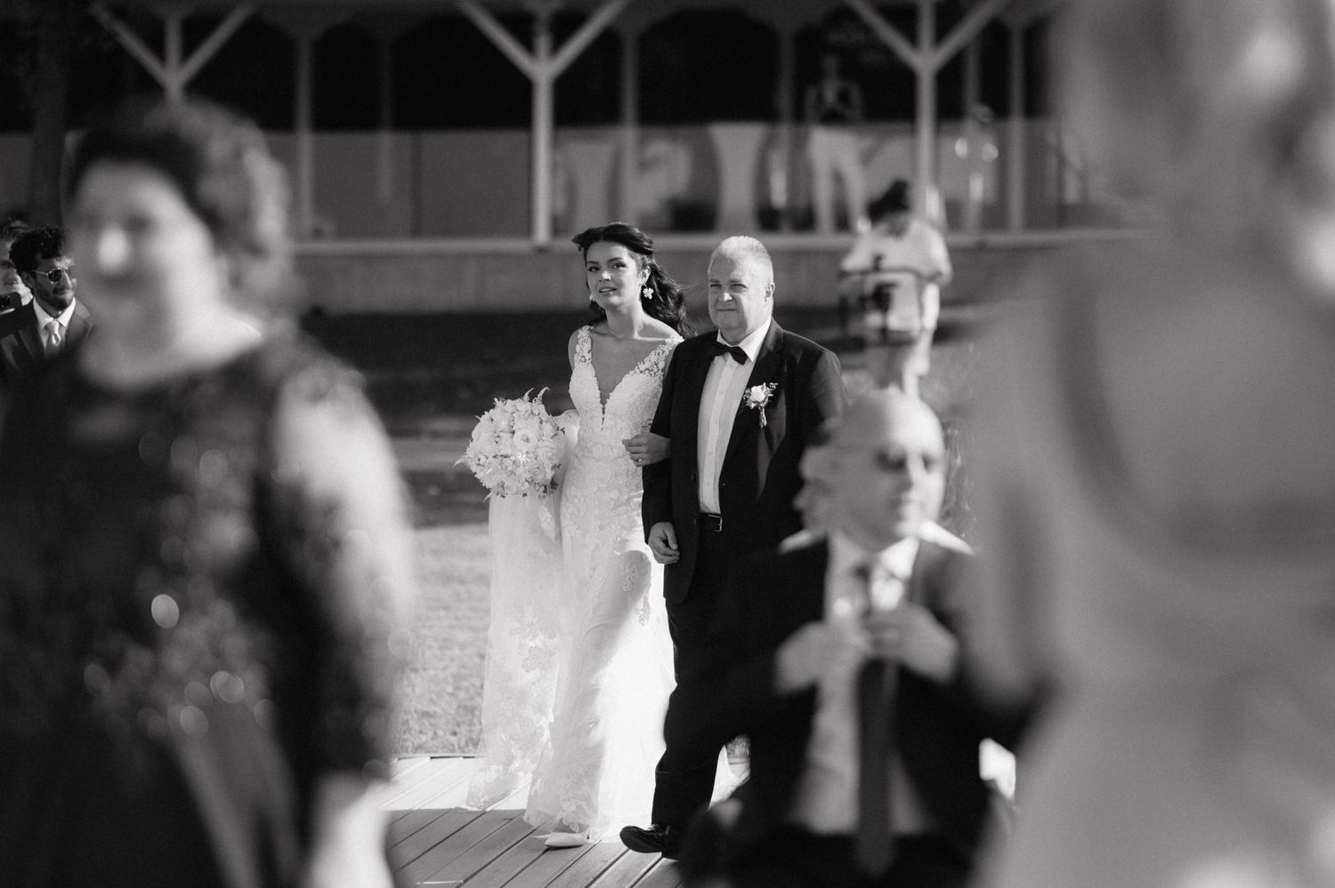 Elegant black and white wedding photograph featuring a formal bridal procession in a traditional ceremony setting.