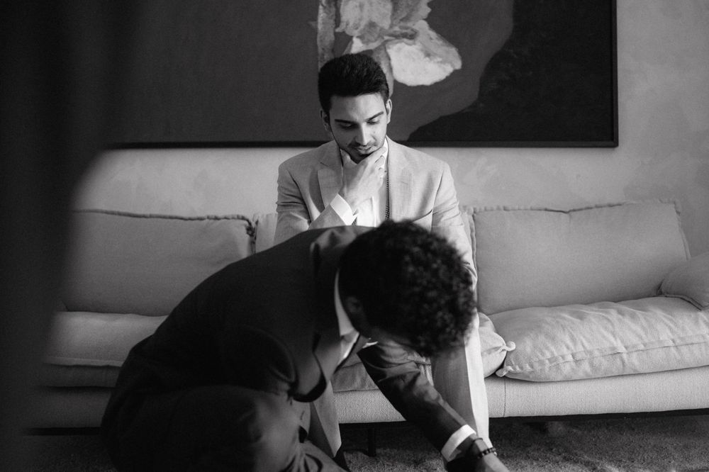 A black and white vintage photograph showing two people seated on a couch in conversation.