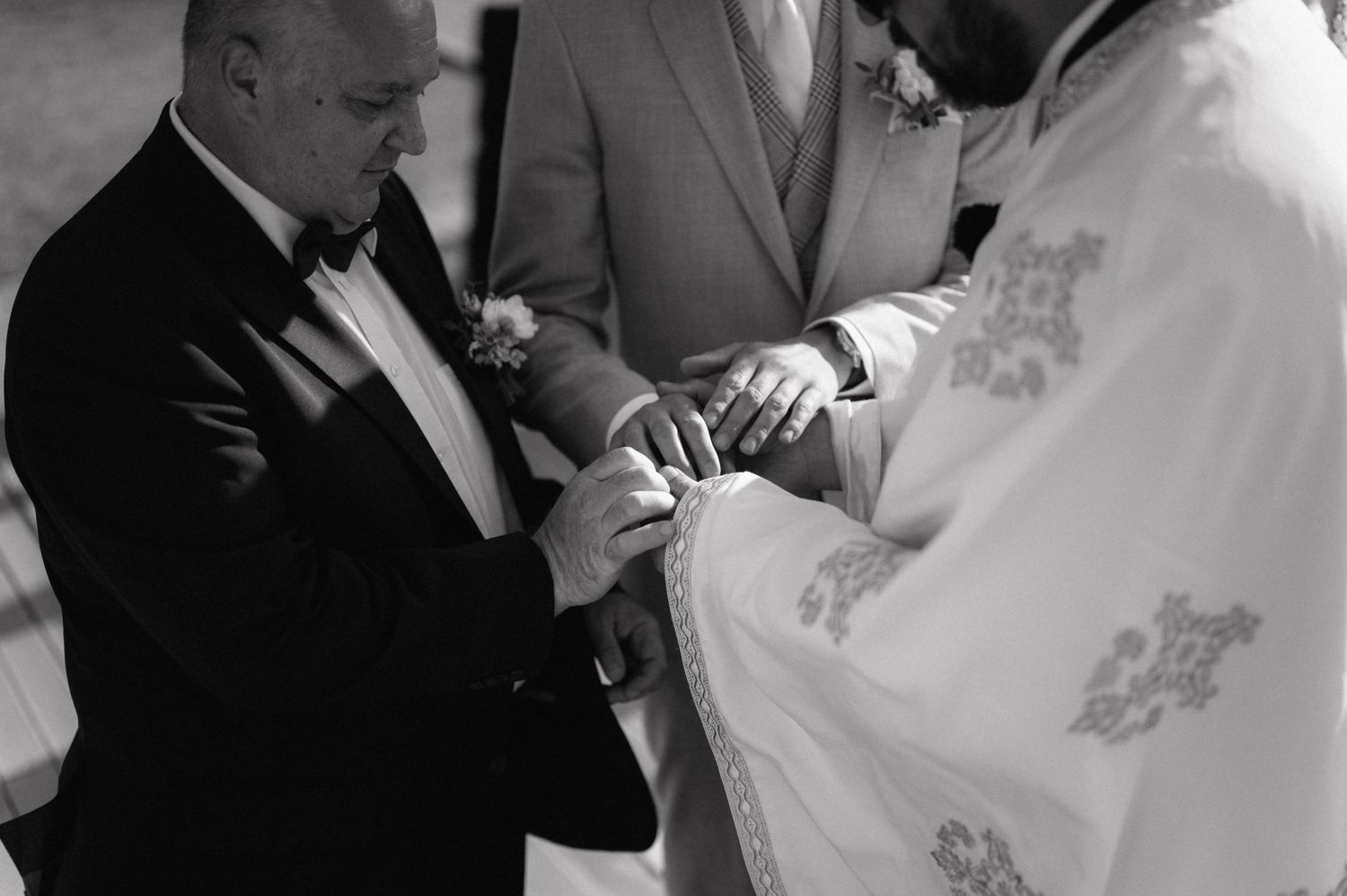 Black and white photo capturing the exchange of wedding rings during a traditional wedding ceremony.