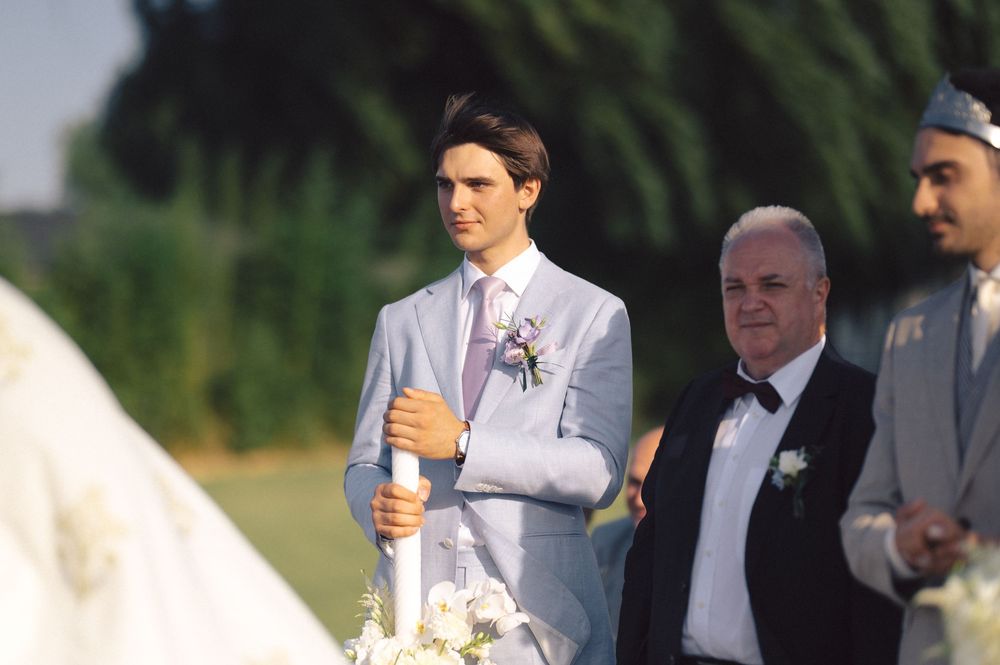 Wedding party members smile and hold champagne glasses during an outdoor celebration.
