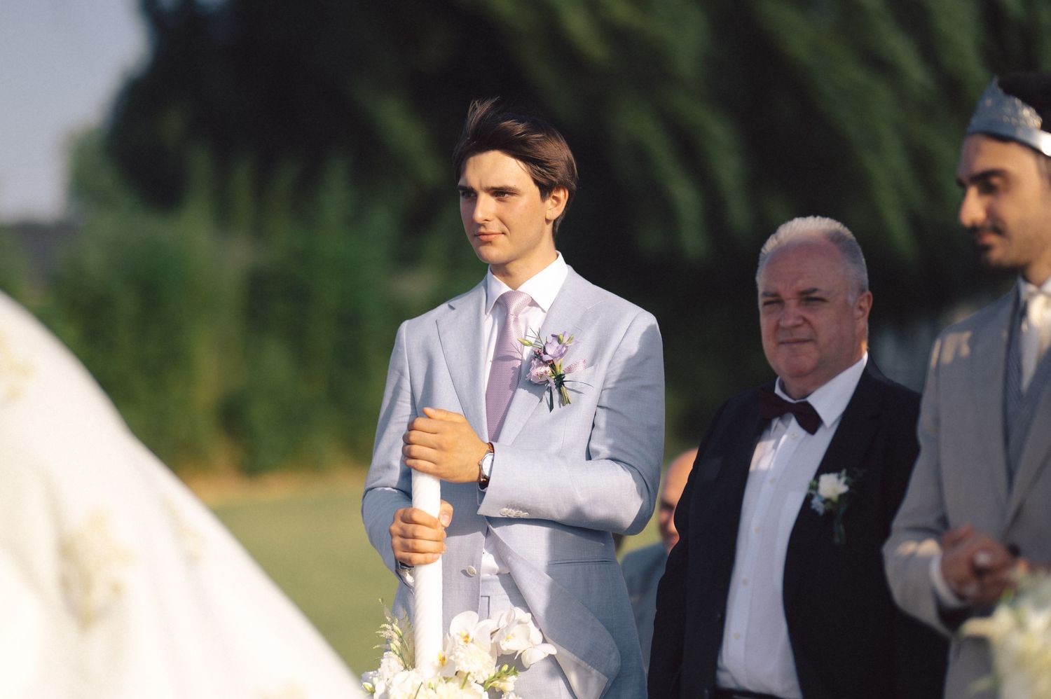 Wedding party members smile and hold champagne glasses during an outdoor celebration.