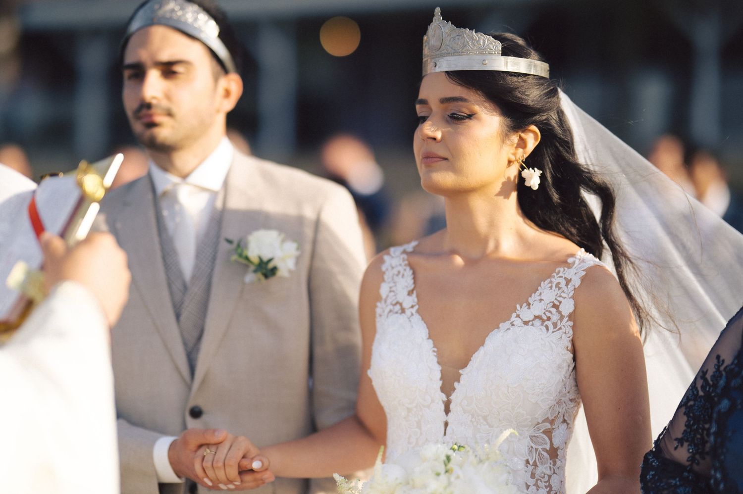 A bride and groom celebrate during their wedding ceremony while guests in formal attire look on.