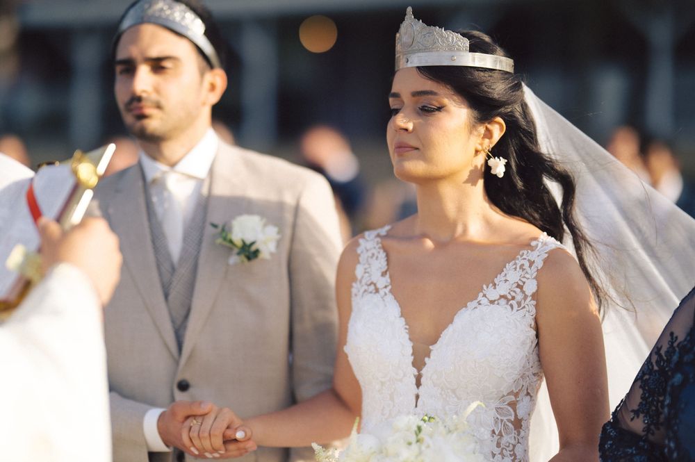 A bride and groom celebrate during their wedding ceremony while guests in formal attire look on.