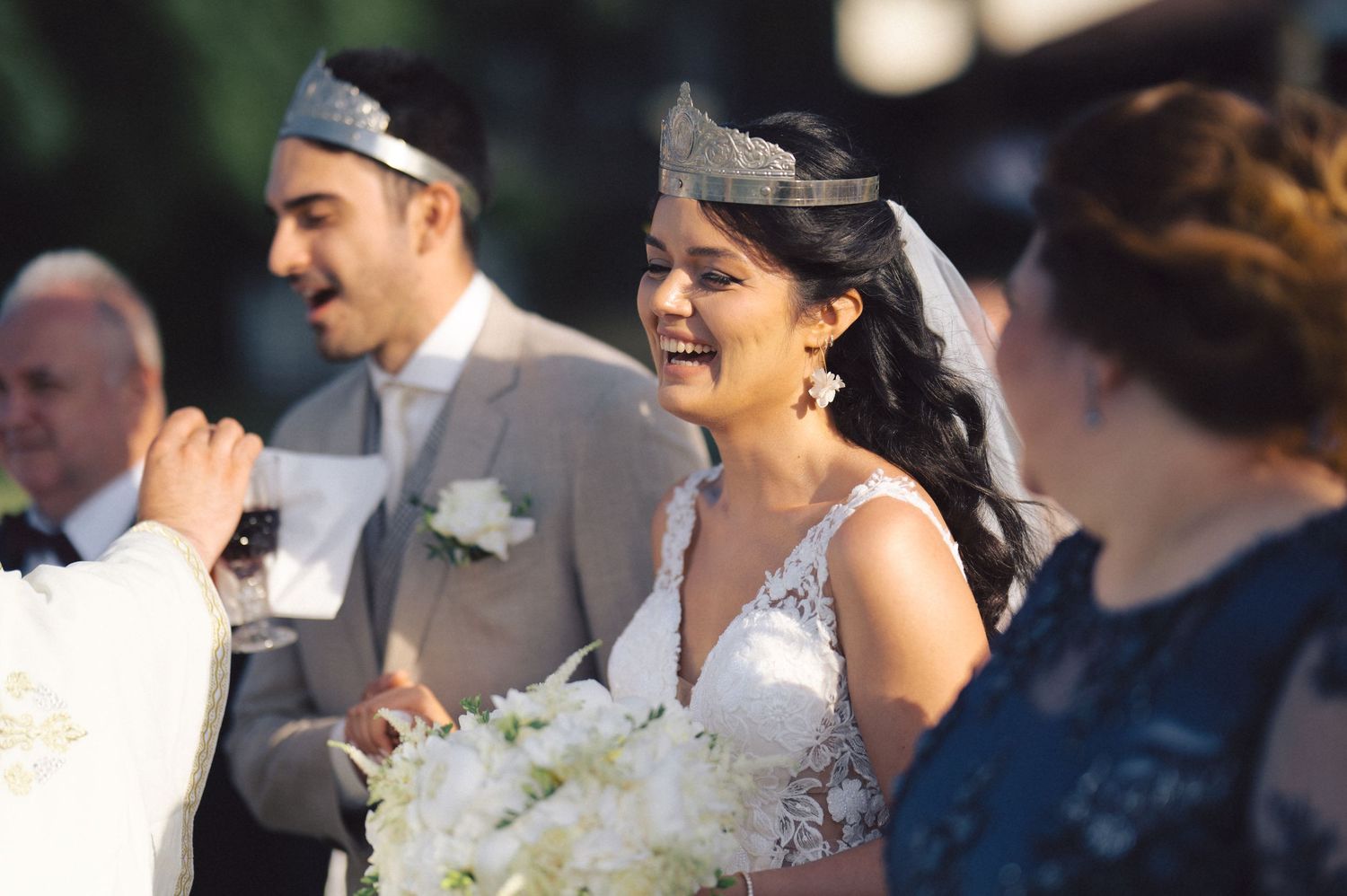 A joyful wedding celebration outdoors with beautiful white floral bouquets on a sunny day.