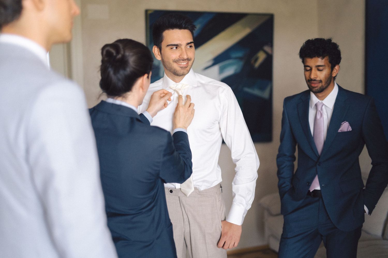 Groomsmen in navy blue suits gather and get ready before a formal wedding ceremony.