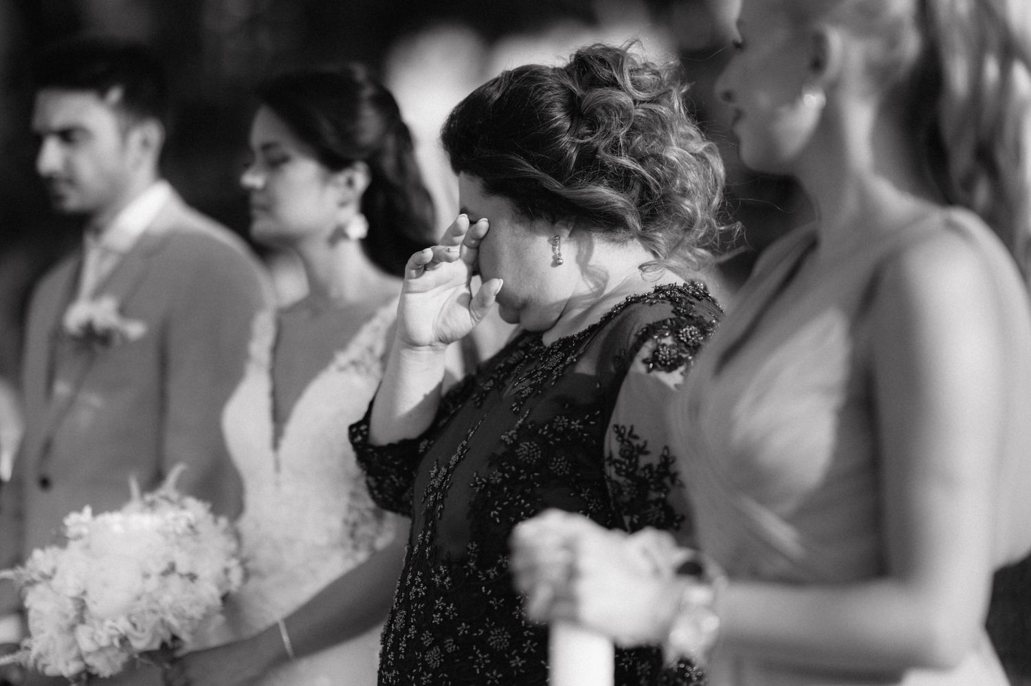 An emotional moment captured in black and white during a wedding ceremony as someone wipes away tears.