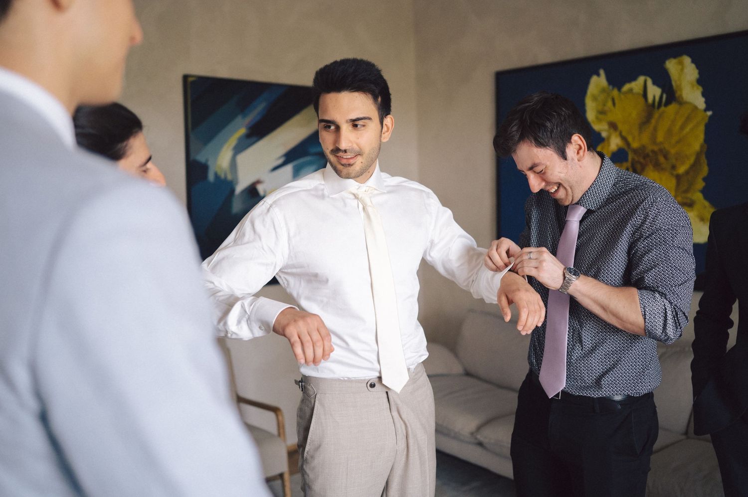 Business colleagues check their watches and compare time during an office meeting near colorful wall art.