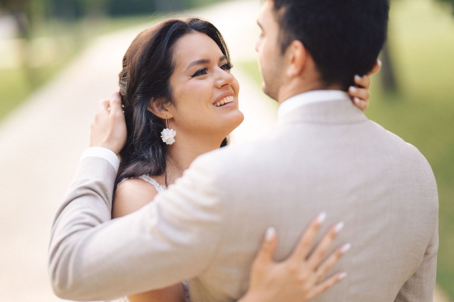 Romantic couple in grey and white wedding attire share intimate moments outdoors in natural green setting.