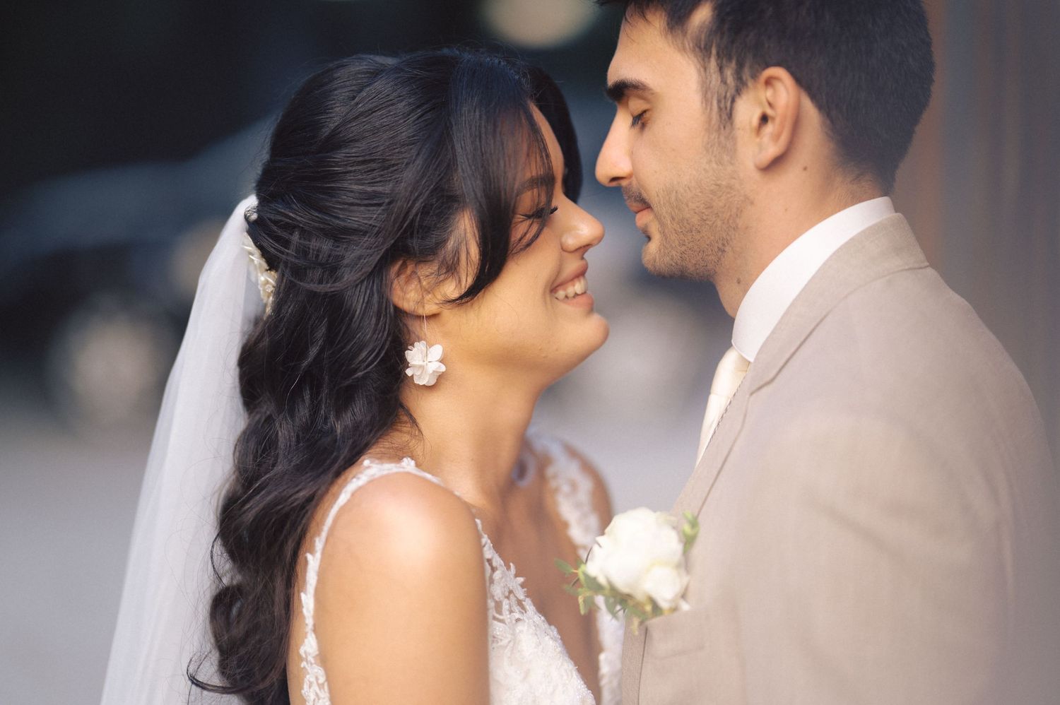 A newlywed couple shares an intimate moment at their wedding, with the bride in white and groom in beige.
