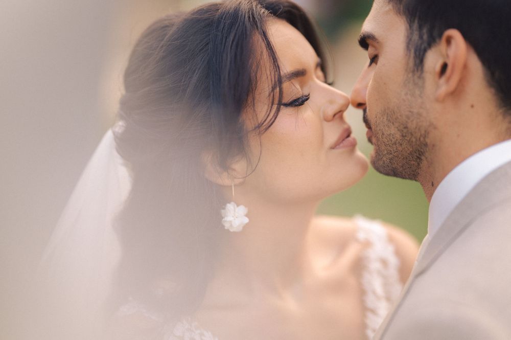 A romantic wedding moment captured through soft focus with the couple sharing a tender kiss under a delicate veil.