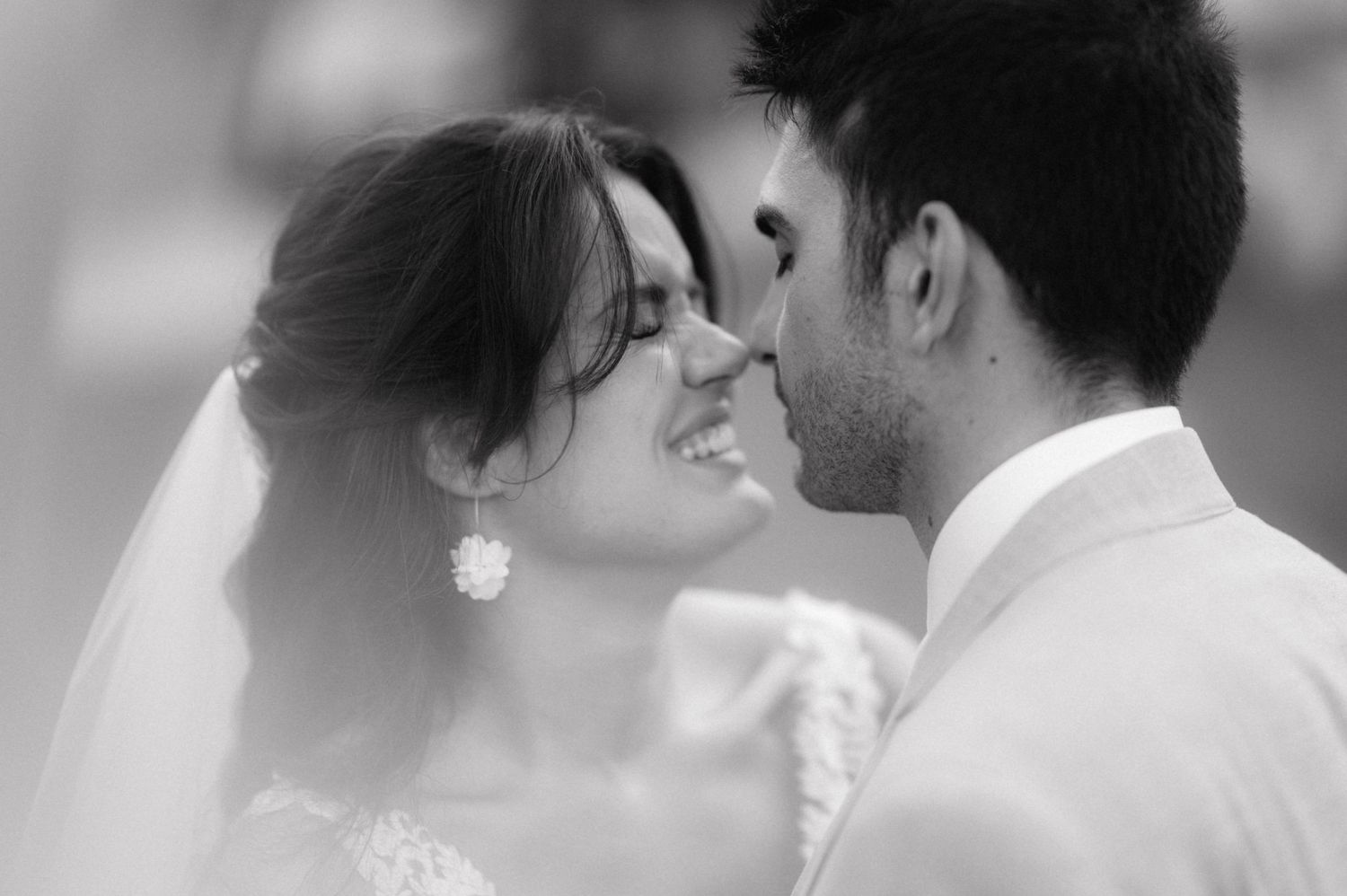 A romantic black and white wedding photo of a loving couple sharing an intimate moment with gentle smiles.