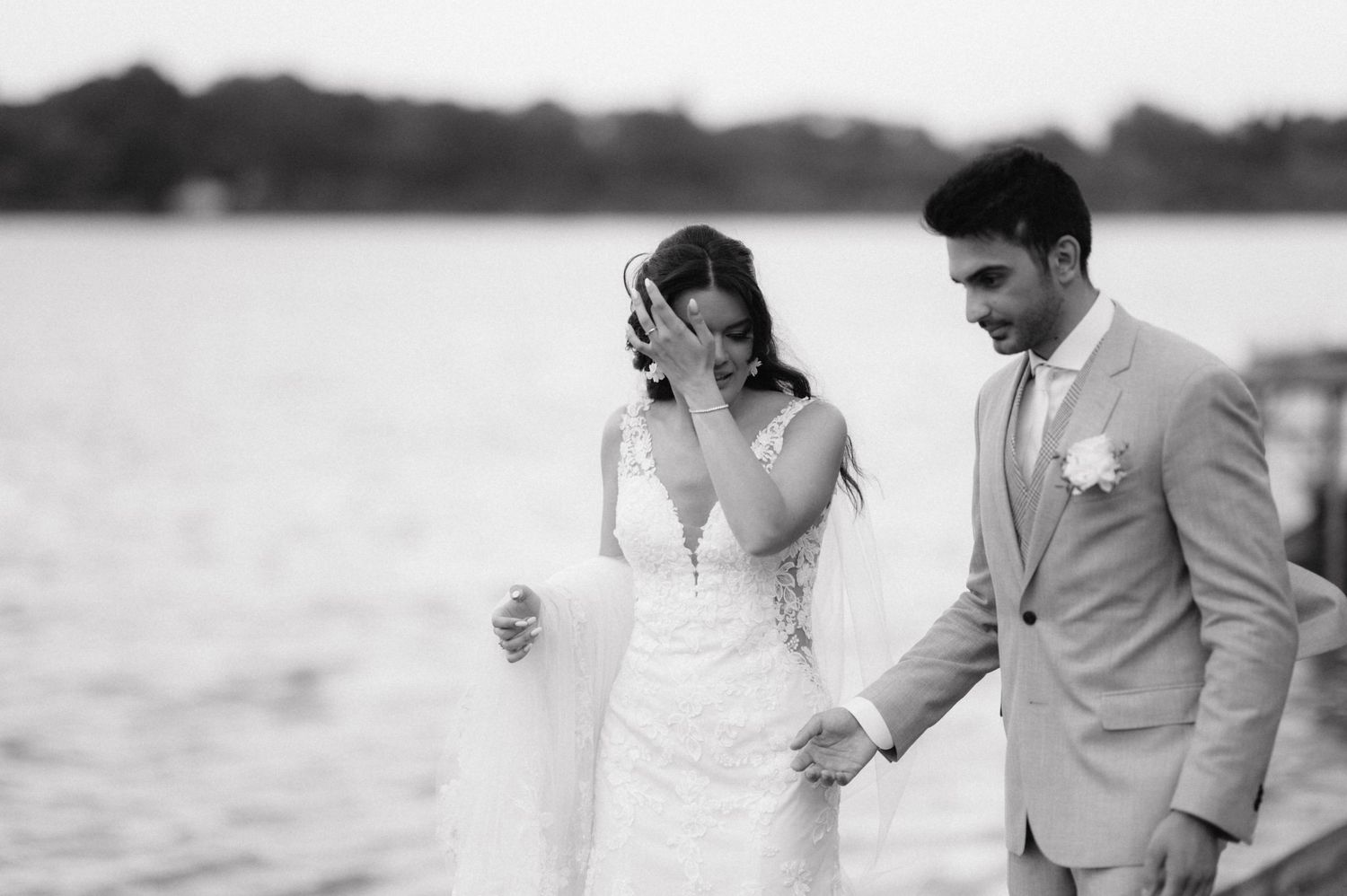 Black and white photos of a romantic bride and groom photoshoot along a waterfront with a cloudy sky background.
